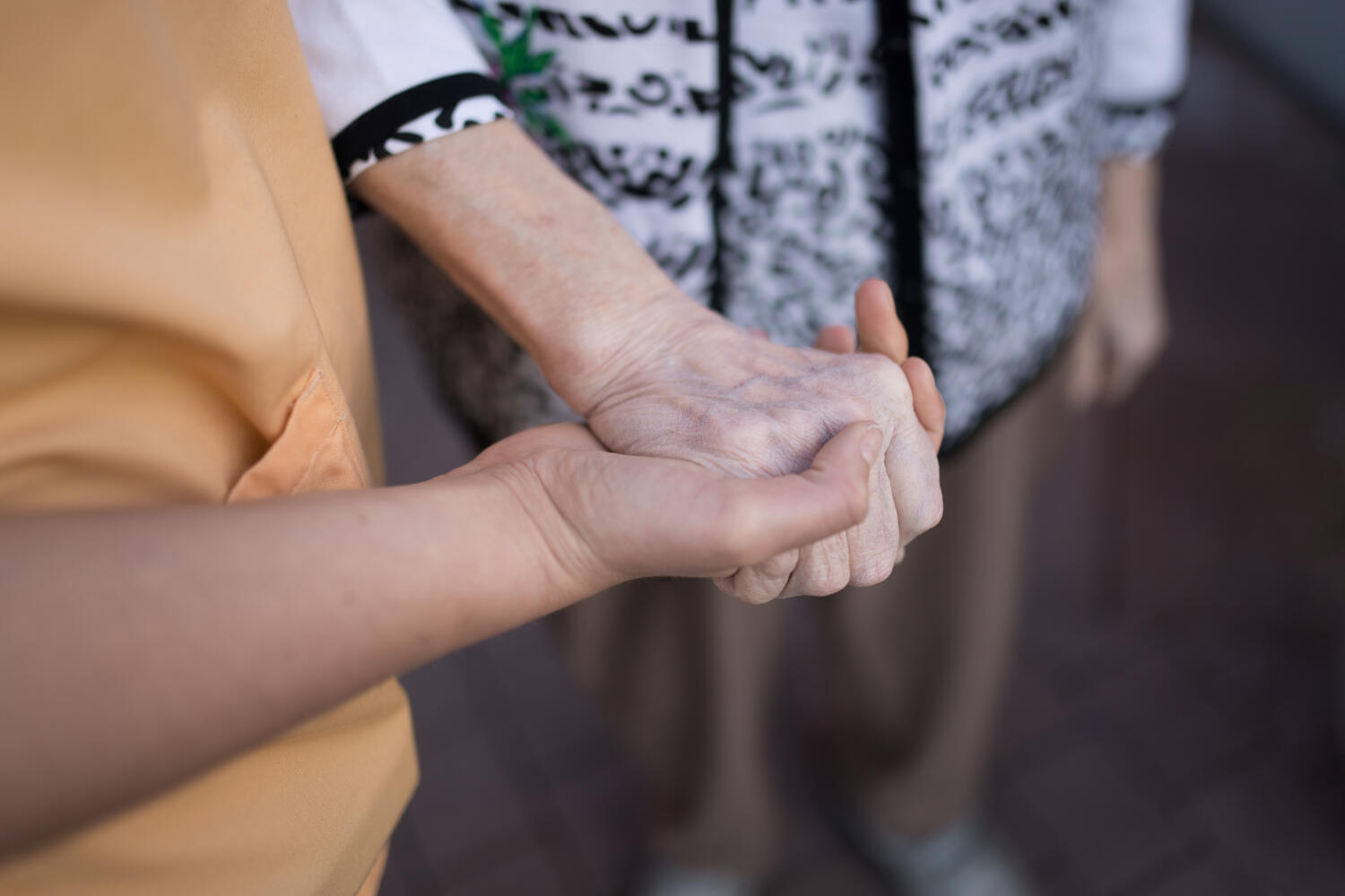 Ein jüngere Hand hält und stützt eine sehr viel ältere Hand.