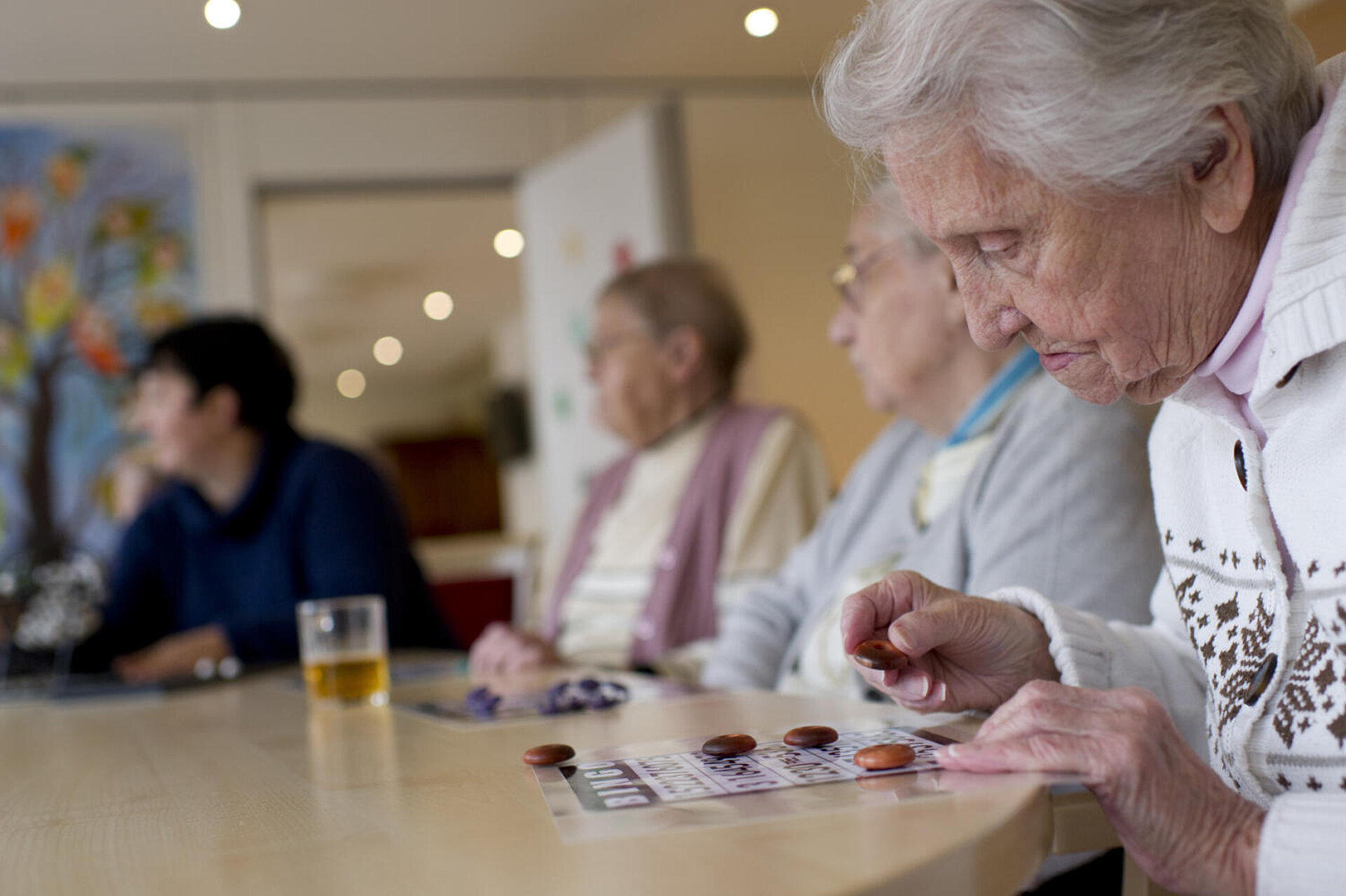 Drei ältere Damen am runden Tisch beim BINGO-Spiel.